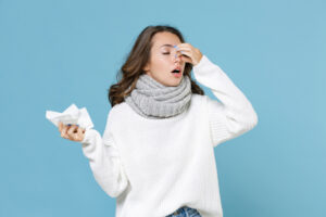 young woman in white sweater scarf hold napkin put hand on nose keeping eyes closed
